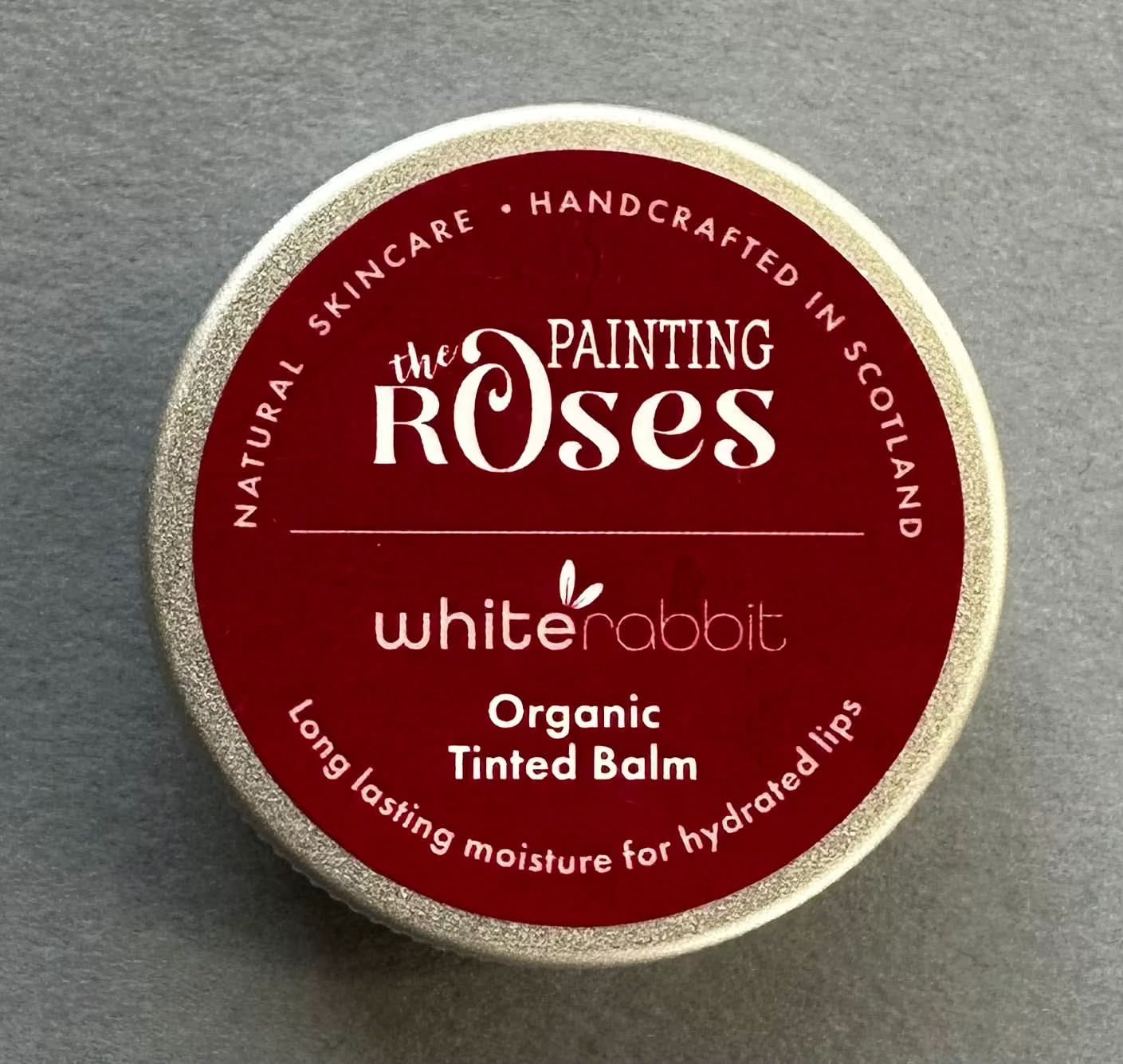 White Rabbit Skin Care organic tinted lip balm and blush balm in a natural shade, showing the product tube and application on skin