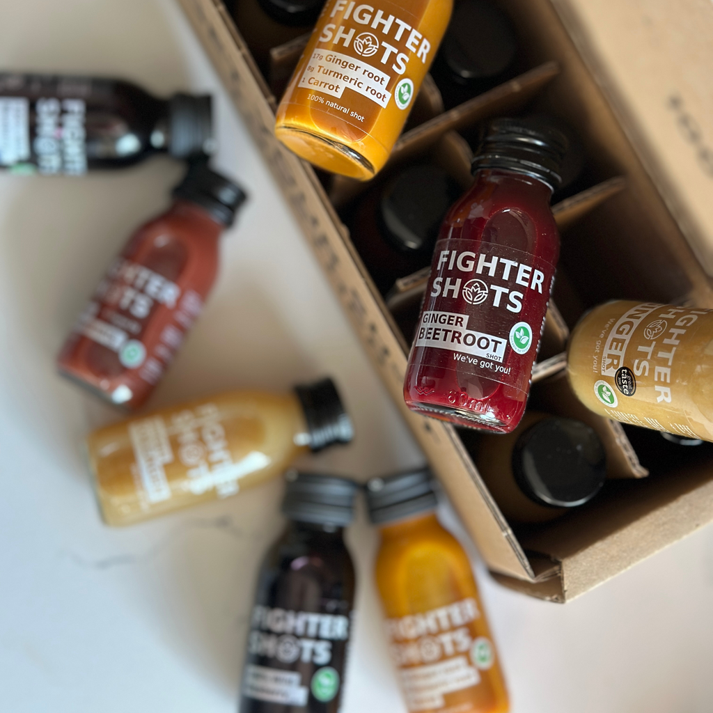 Fighter Shots vegan wellness shot with carrot, ginger, and turmeric in a 60ml glass bottle, displayed with a wooden background.